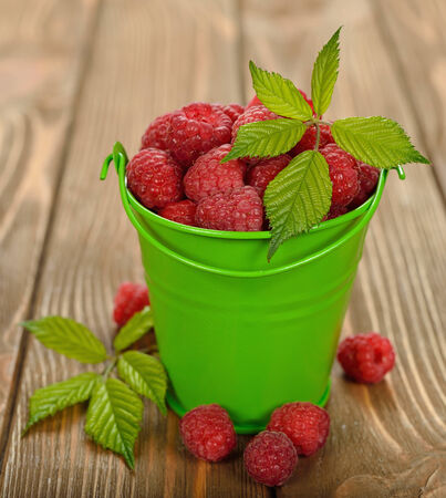 fresh raspberries in green bucket on brown backgroundの写真素材
