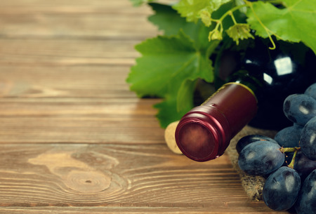 Bottle of wine and grapes, closeup on a brown backgroundの写真素材