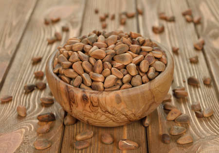 pine nuts in a wooden bowl on a brown backgroundの写真素材