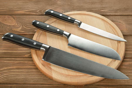 Set of kitchen knives and cutting board on a brown background