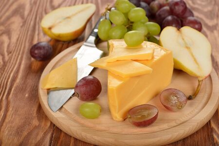 Cheese and grapes on a brown background
