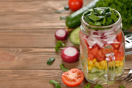 Fresh vegetable salad in Mason jar on a brown backgroundの写真素材