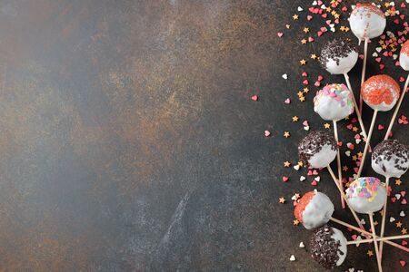 Various cake pops decorated with white chocolate on a brown background