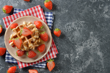 Traditional waffles with maple syrup and strawberries on a gray backgroundの写真素材
