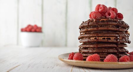 Chocolate pancakes with raspberries on white background