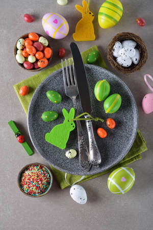 Various Easter decorations and sweets on a gray background