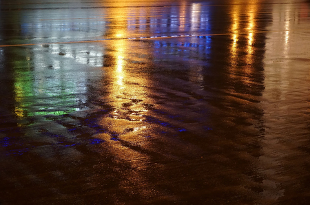 Colorful water reflection on the road. City lights reflected in puddle. Rain weather, puddle of infinity, rain nightの写真素材
