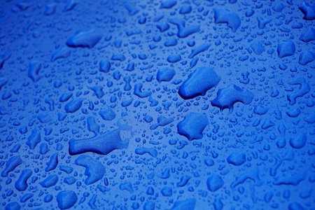 Rain drops on blue car. Raining spring weather. Rain grops on blue glossy backdrop. Raining season. Rainy spring sunshine day.の写真素材
