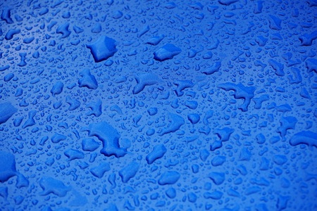 Rain drops on blue car. Raining spring weather. Rain grops on blue glossy background. Raining season. Rainy spring sunny day.の写真素材