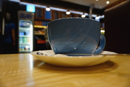 Blue half-liter mug stands on light table. In background refrigerator with hanging luminous chandeliers on ceiling.の写真素材