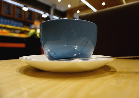 Blue half-liter mug stands on light table. In background hanging luminous chandeliers on ceiling. Frame colors: blue, brown, white, orange, beige.の写真素材