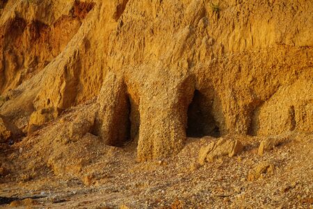 The sandy mountain isolated is bright orange with cracks and traces of landslides. The photo is useful as a background, texture.の写真素材
