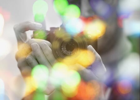 Close-up view of a man's hands with newest camera with lens in his hands. Bright round colorful circles outside focus in the frame in the foregroundの写真素材