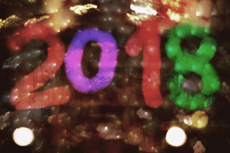 Colorful numbers 2018 against background of blurred shining and moving New Year's lights. Frame colors: violet, purple, lilac, red, green, yellow, black, brown.の写真素材