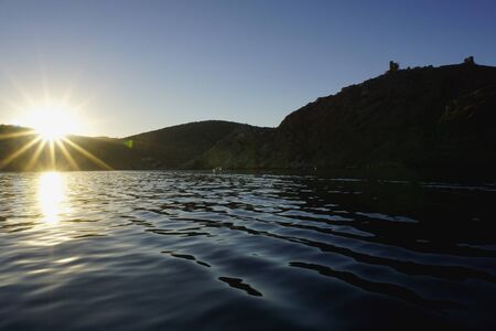 Balaklava, Sevastopol, Crimea, Russia. Landscape with sun with long rays over Black sea, crimean mountains. Sunset timeの写真素材