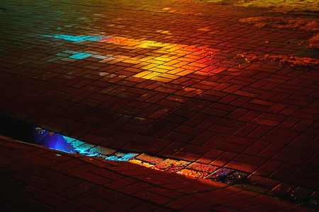 A wet colored spot on the paving slab. Image colors: red, yellow, black, blue, purple.の写真素材