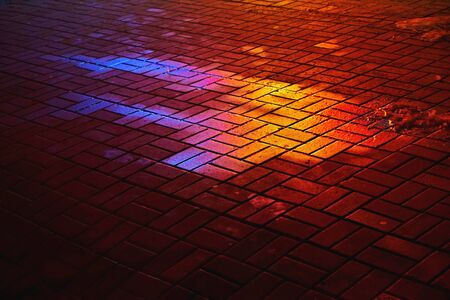 A wet colored spot on the paving slab. Image colors: red, yellow, black, blue, purple.の写真素材