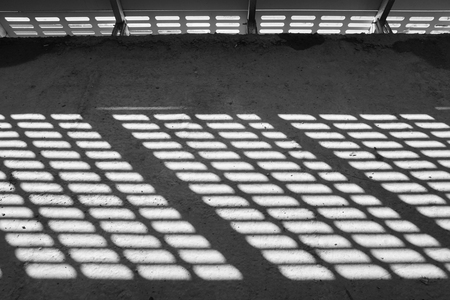 Shadow and light. Black and white. Sunny light from metal lattice, abandoned unfinished shoping mall. Perspective lines backgroundの写真素材