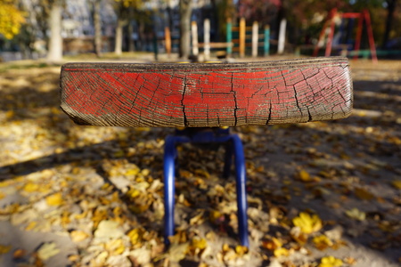 A playground with a red shawl for two children. Old peeling paint, sunny golden autumn. Yellow...