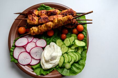 Chicken kebabs with vegetables on a clay plateの写真素材