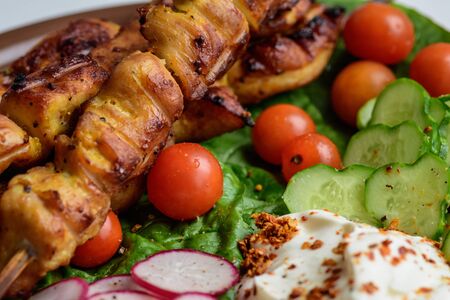 Chicken kebabs with vegetables on a clay plateの写真素材