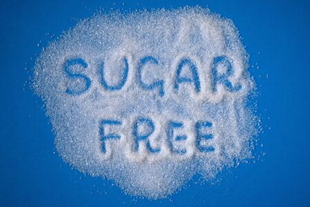 Sugar Free words hand written on a heap of white sugar on a blue background top view. Stop diabetes and excessive sugar intake concept. Healthcare, unhealthy diet concept.の写真素材