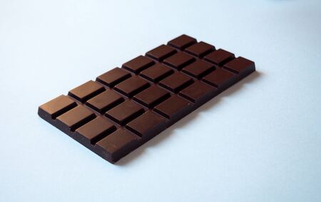 Dark chocolate bar isolated on gray background from the side view