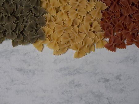 Traditional italian farfalle pasta in national flag tricolor style on gray marble background with...
