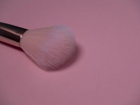 Pink make up brush for applying powder and blush on a pink background. Professional makeup artist tool close up.の写真素材
