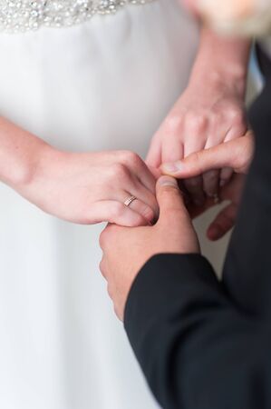 The bride and groom in wedding dresses standing next to each other and holding hands. On the finger of the bride wearing a wedding ringの写真素材