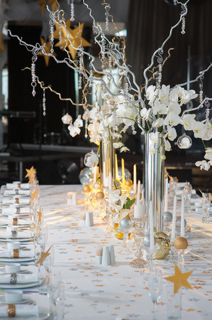 The branches of orchids in vases on the holiday table. Decorative branch with crystal elements decorated table.の写真素材