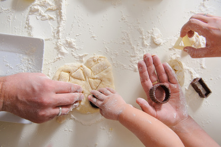 Three pair of Hands make homemade cookies, hands only. Cookie cutters for baking cookies with dough and flour in the background.の写真素材