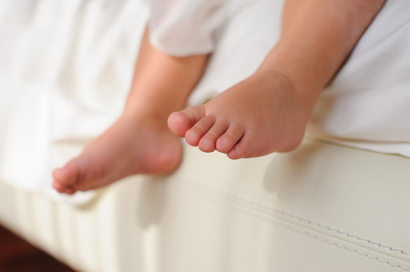 Baby or Children foot  sitting on the white bed, closeup.の写真素材