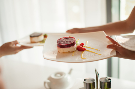 Dessert on a white plate, hand a waiter serving plate. Selective Focus.の写真素材
