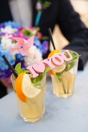 handmade pink wooden letters, I love you on glasses with a cocktail. Focus on the sign. Blurred groom and bouquet in the background.の写真素材