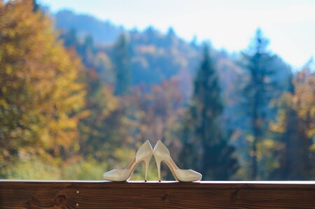 Beautiful wedding shoes on a background of beautiful mountain landscape. Brown wooden beams balcony.の写真素材