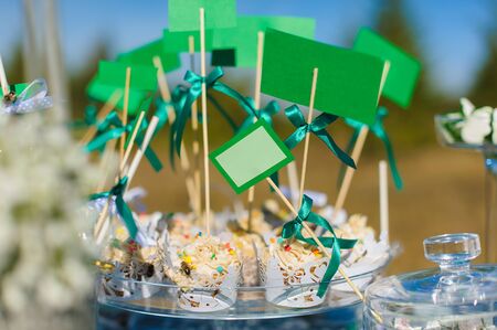 Candybar cupcakes and cakes with tags empty space for writing. Sweets on a table in the open air, outdoors, nobody.の写真素材