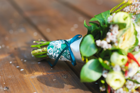 bunch, bouquet  turquoise ribbon and white lace on the old brown wooden table. outdoors. focus on a ribbon with a bow.の写真素材