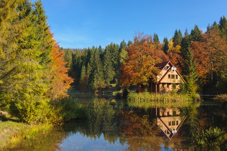 The scenic landscape. house by Lake. Reflection in water. Forest and mountains surround the house. autumn.の写真素材
