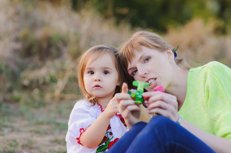 Young mother and little daughter play with toys in summer parkの写真素材
