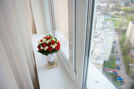 Wedding bouquet in a vase on a windowsill in the apartment on a high floor. View from above.の写真素材