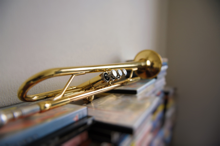Old trumpet lays on a stack of DVD boxes in the room. Selective Focus.の写真素材