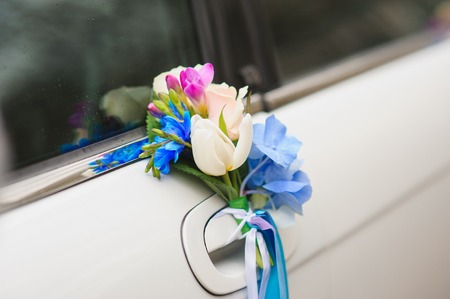 Wedding car handle decorated with white, blue, red flowers and ribbons.の写真素材