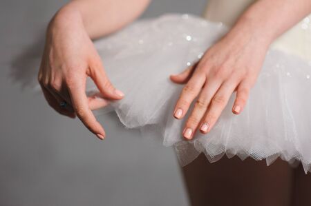 Close-up. hands of ballerina on a background of white tutu.の写真素材
