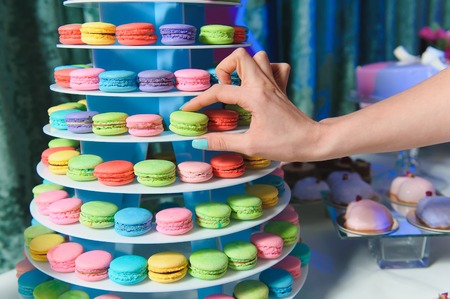Female hand taking tasty colorful macaroons from towerの写真素材