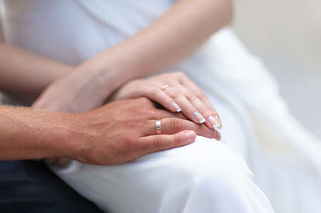 Closeup of hands of bride and groom with wedding rings. Woman in white dress.の写真素材