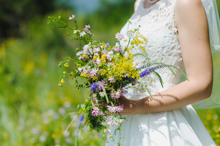 The bride holds in hand a bouquet of wildflowersの写真素材