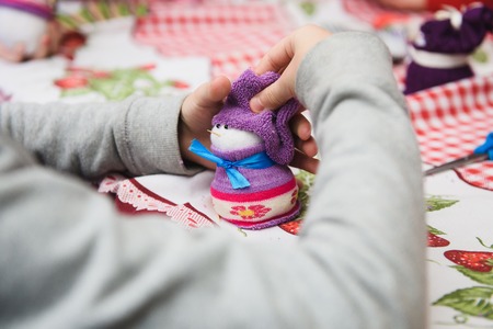 Happy kid doing craft. Small child holding a felt Christmas snowman in hands. Workplace in kindergarten, school or home. Kids Christmas crafts idea. Children winter creativityの写真素材