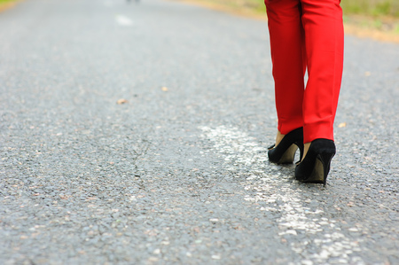 Lonely girl on the road. Lonely girl walking along the road. Road markings.の写真素材