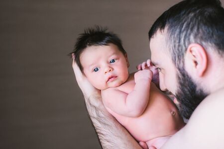 Newborn baby and dad. Happy father holding and plays with his baby boy indoors.の写真素材